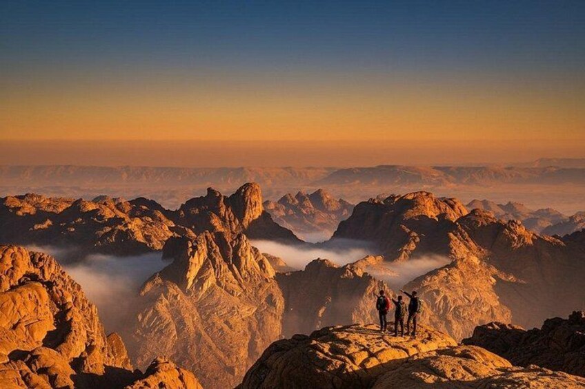 A mountainous landscape with rocky peaks and a group of people standing on a ridge. 1