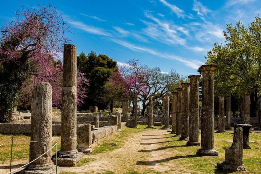 Ancient stone columns in a garden with flowering trees. 1