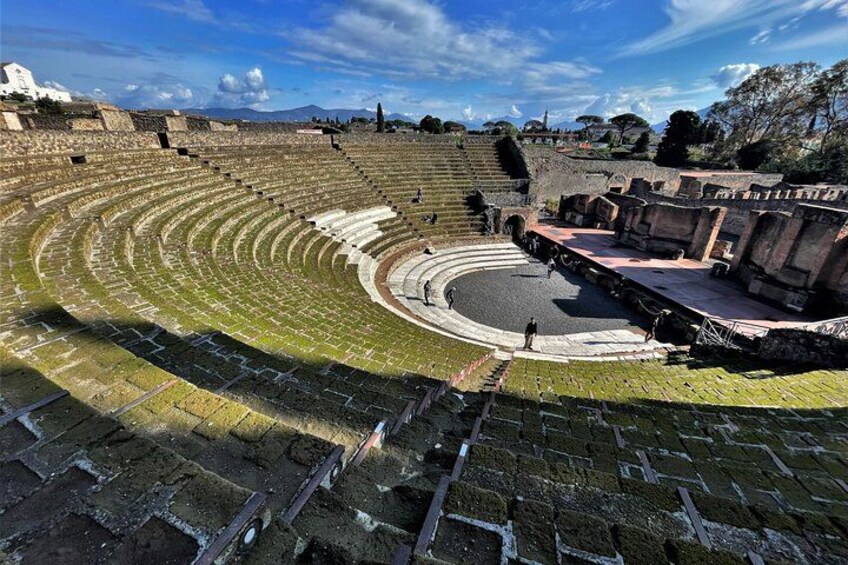 Un antiguo anfiteatro con asientos escalonados y un escenario central. 2
