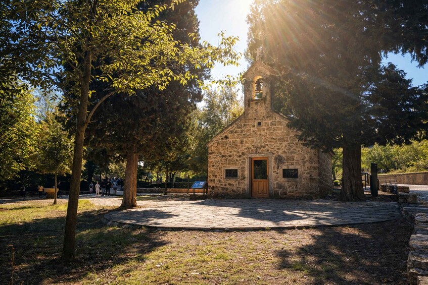A stone church with a bell tower, surrounded by trees and a cobblestone path. 4