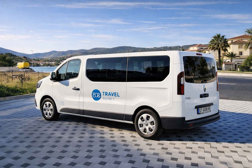 A white van parked on a patterned pavement with a blue sky and mountains in the background. 5