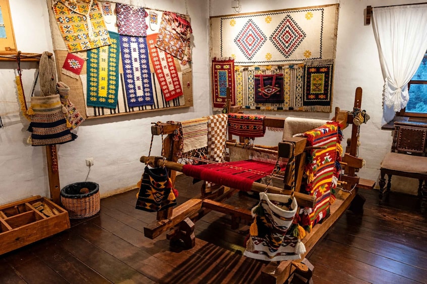 A traditional weaving loom with colorful textiles and a patterned wall hanging. 2