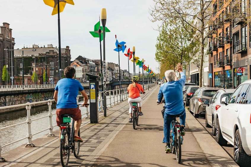 A canal with cyclists and parked cars on the sidewalk. 1