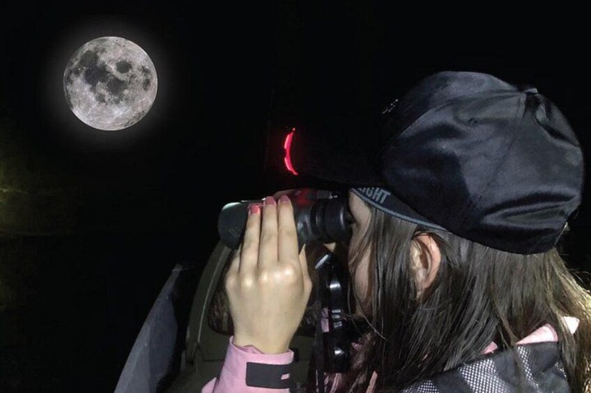 Une personne tenant un appareil photo avec la lune en arrière-plan. 1