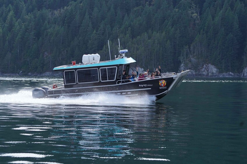 A speedboat with passengers on a lake surrounded by forest. 5