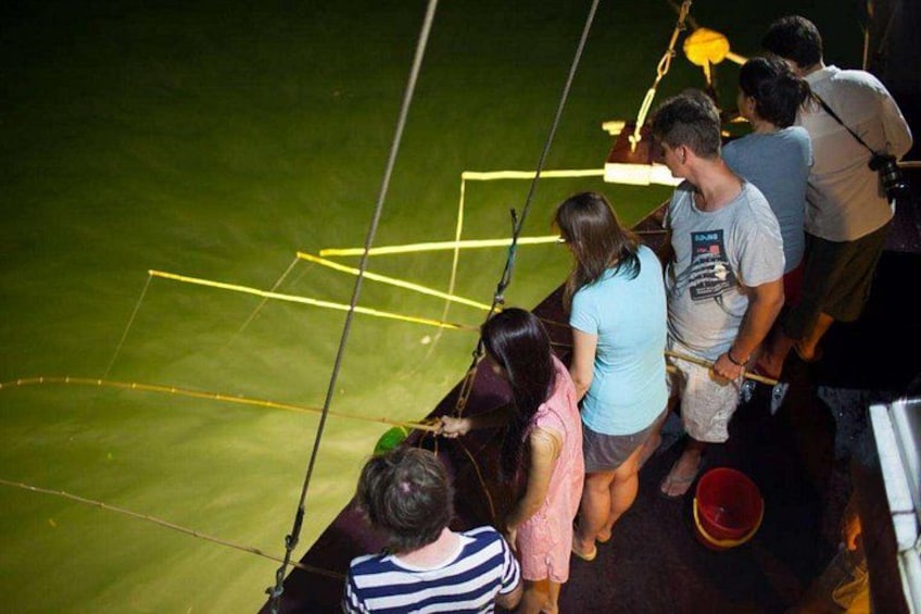 People on a boat with a green deck, ropes, and a net. 3