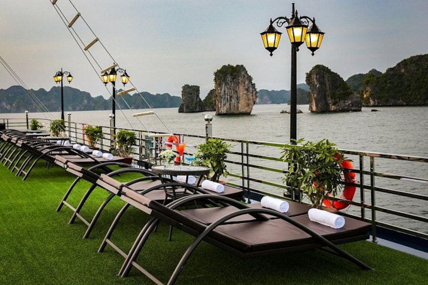 A riverside dining area with tables and chairs, a railing, and a view of the water and rock formations. 5