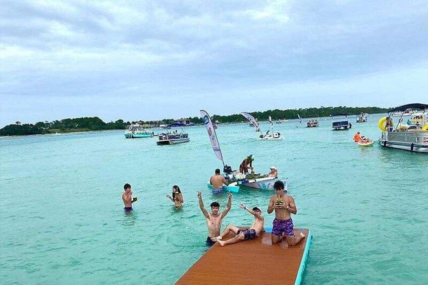 A group of people on a wooden boat in a turquoise sea with several other boats in the background. 2