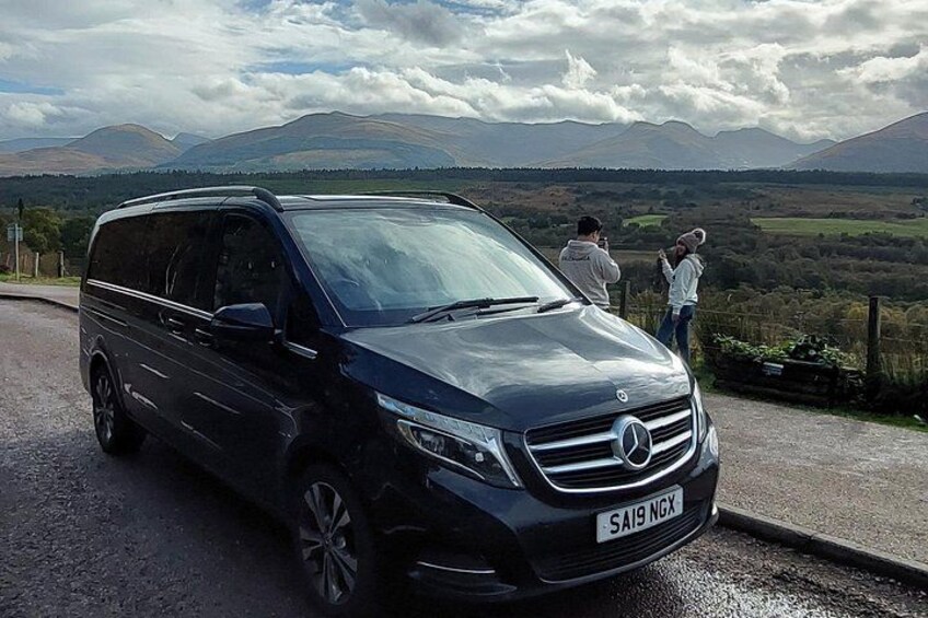 Un SUV Mercedes-Benz noir est garé sur une route, avec un paysage pittoresque en arrière-plan. 2