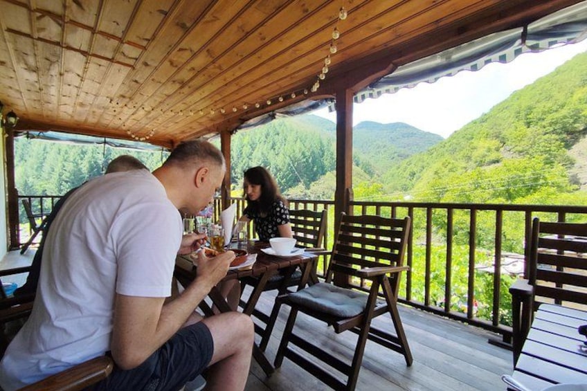 A wooden deck with tables and chairs overlooking a mountainous landscape. 2