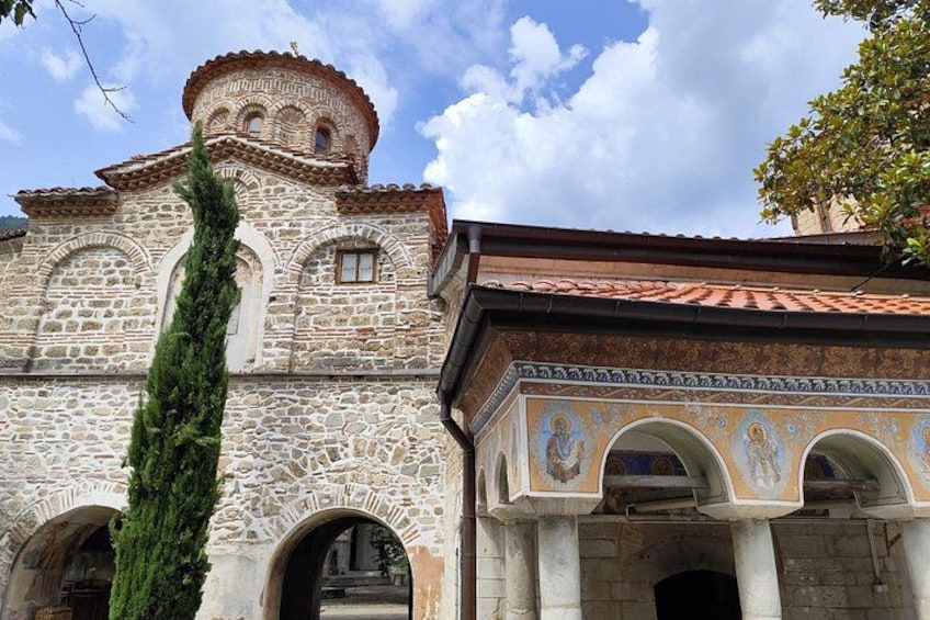 A stone building with a tiled roof, arched doorways, and a decorative tower. 5