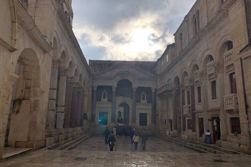 Un cortile con edifici in pietra, portali ad arco e un'area aperta al centro. 2