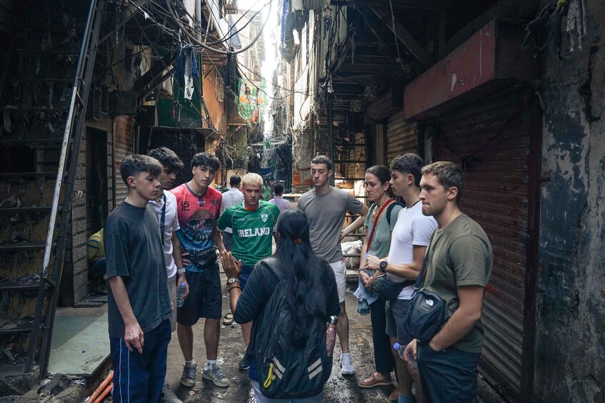 Un groupe de personnes se tient dans une ruelle étroite, avec des bâtiments de chaque côté. 5
