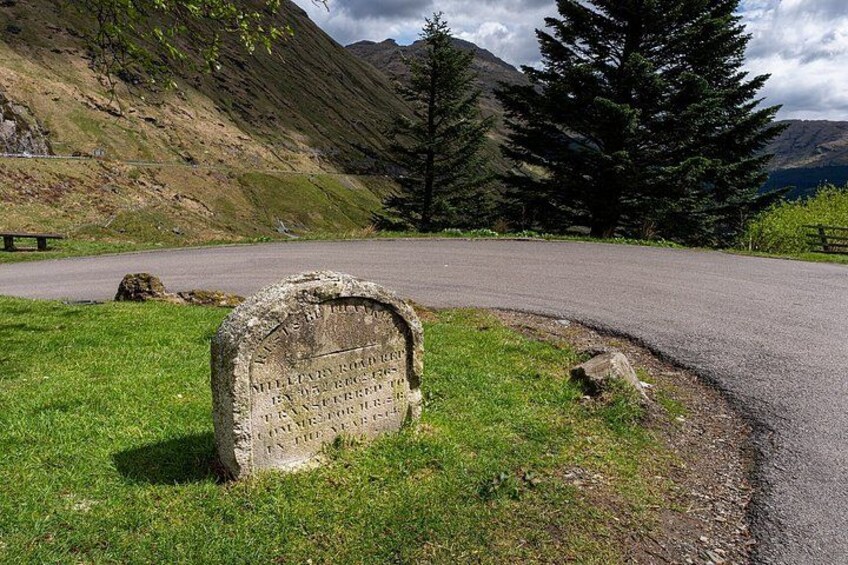 A winding road, a stone monument, a picnic table, and a mountain backdrop. 2