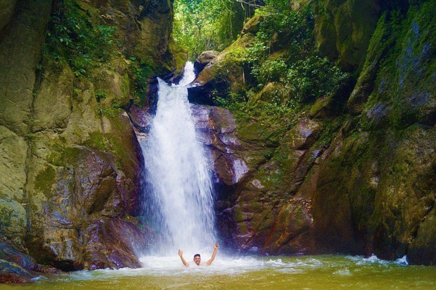 A waterfall in a rocky gorge with lush greenery. 1