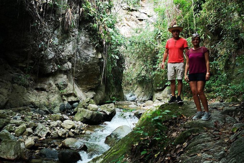 A rocky stream with people standing on a ledge. 5