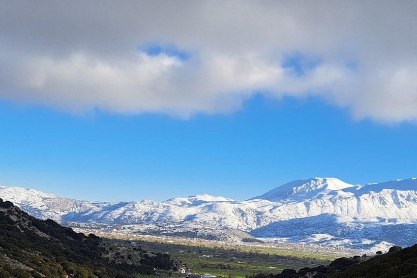 A mountain range with snow-covered peaks under a partly cloudy sky. 3