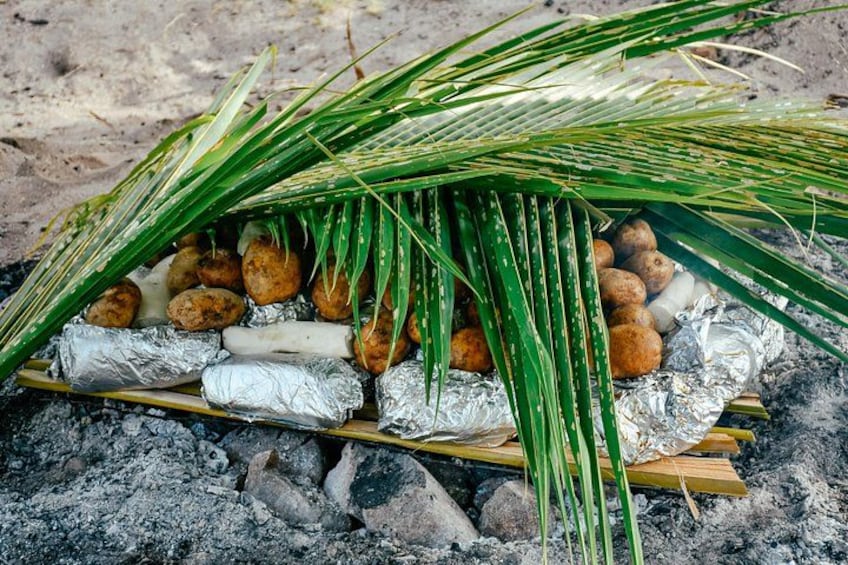 Un dispositif de cuisson où les aliments sont enveloppés dans du papier d’aluminium et placés sur du charbon de bois. 5