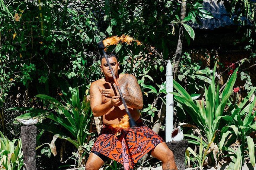 Une personne vêtue d’un costume traditionnel, tenant un bâton, entourée d’une végétation luxuriante et d’une structure blanche. 4