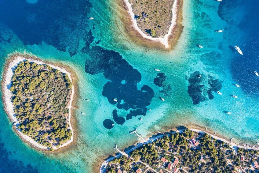 Vogelperspektive einer Küstenregion mit klarem, blauem Wasser, einer herzförmigen Insel und einer kleinen Halbinsel mit Gebäuden. 1
