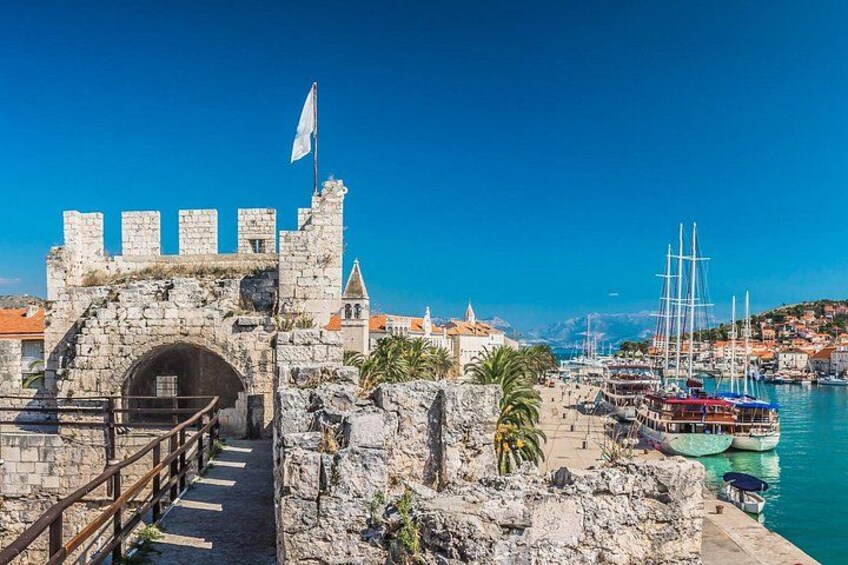 Eine historische Steinbrücke, ein klares blaues Meer und ein Hafen voller Boote. 2