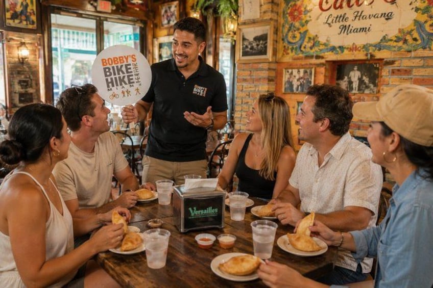 Un gruppo di persone che cenano in un ristorante con un cartello che riporta la scritta 'Bobby's Bike Hike Miami'. 4
