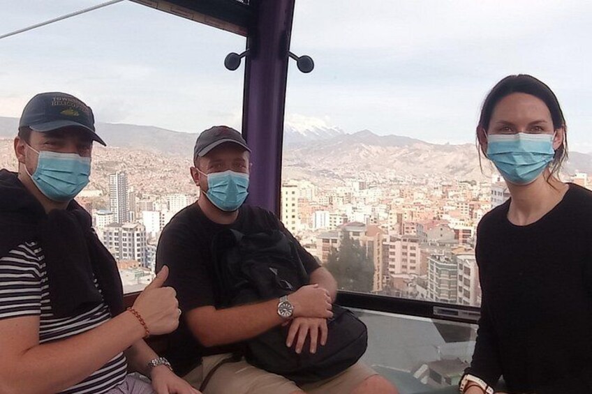 Three people sitting on a bus with a cityscape and mountains in the background. 2