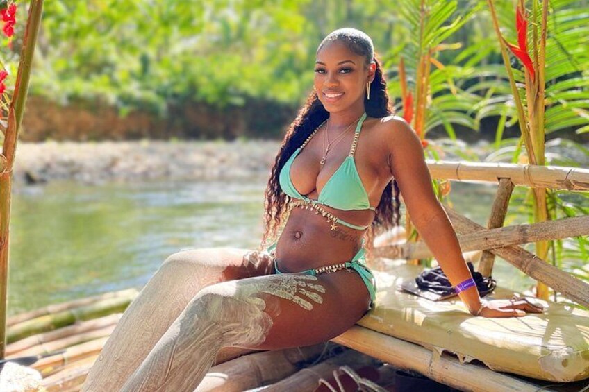 A person sitting on a wooden platform by a body of water, surrounded by greenery. 4