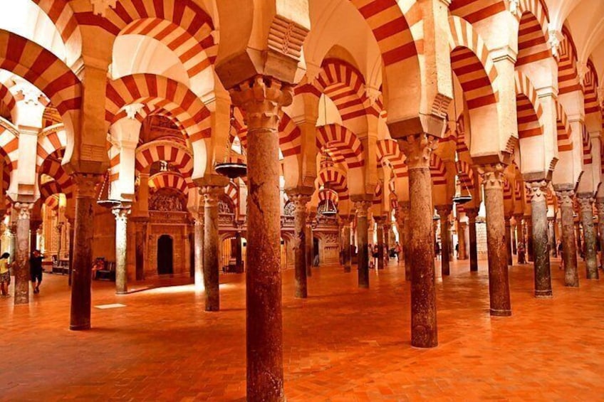 A large interior space with high arches and columns, featuring a patterned ceiling and a polished floor. 5