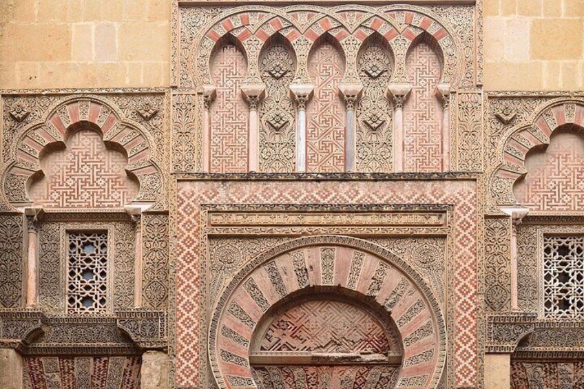 Intricate geometric and floral patterns on a building facade, featuring arches and detailed stonework. 2
