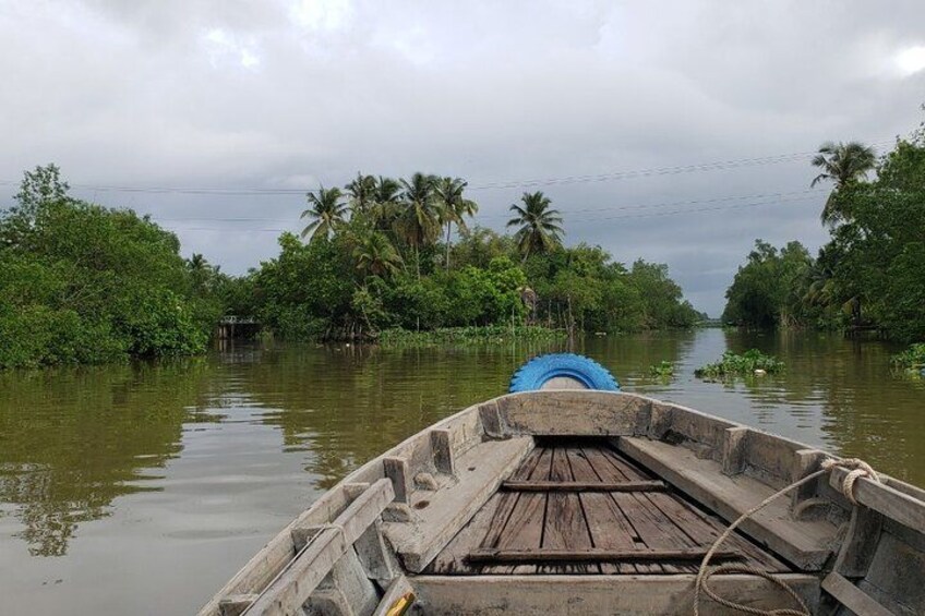 Un bote de madera en un río tranquilo rodeado de vegetación exuberante y palmeras. 2