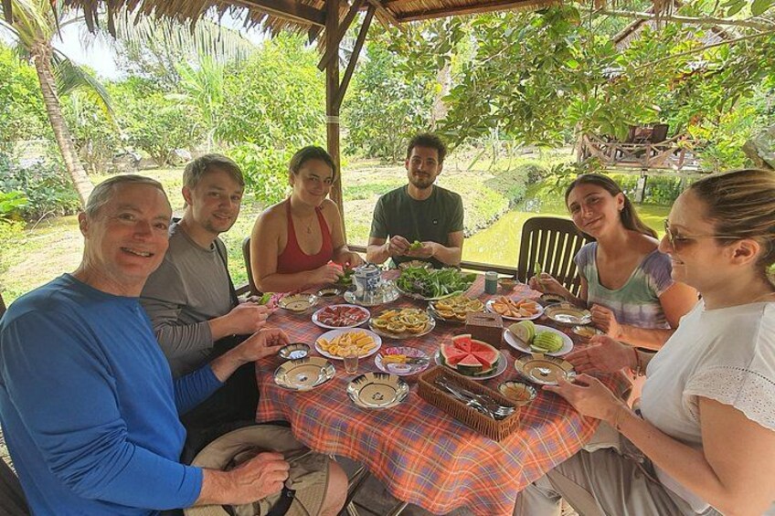 Un grupo de personas cenando al aire libre en una mesa con diferentes platos. 2