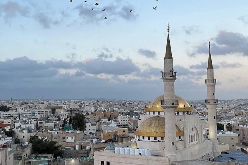 Une mosquée dotée de deux minarets et d’un dôme, entourée d’un paysage urbain. 5