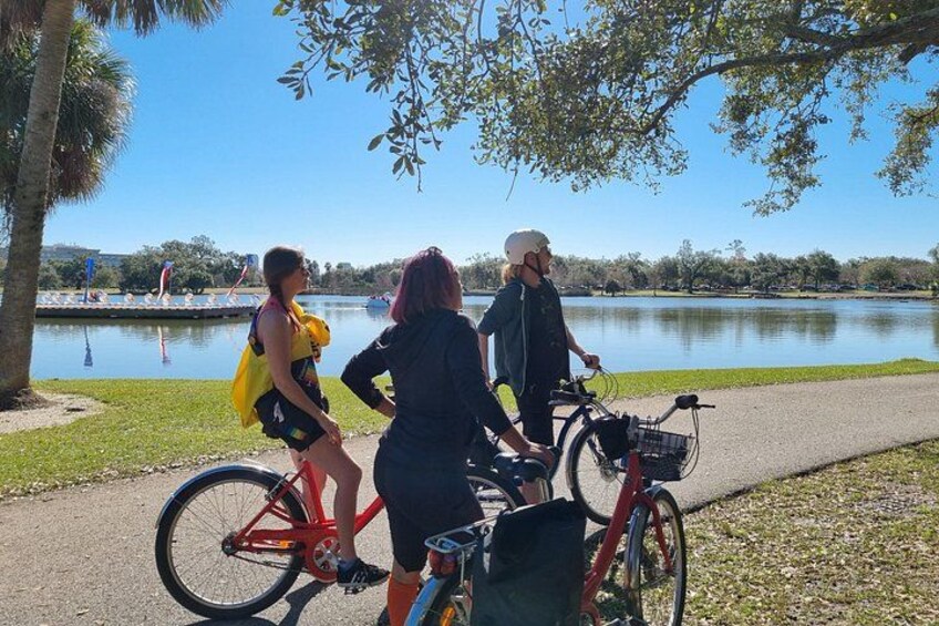 Three people on bicycles near a lake with a clear sky. 4