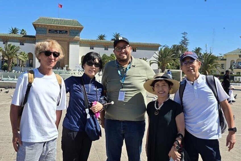 A group of people standing in front of a building with a green roof and palm trees in the background. 4