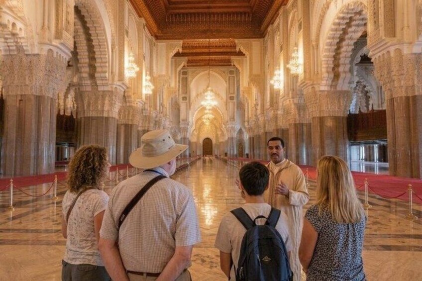 A group of people walking through a grand, ornate hallway with high ceilings and intricate architectural details. 1