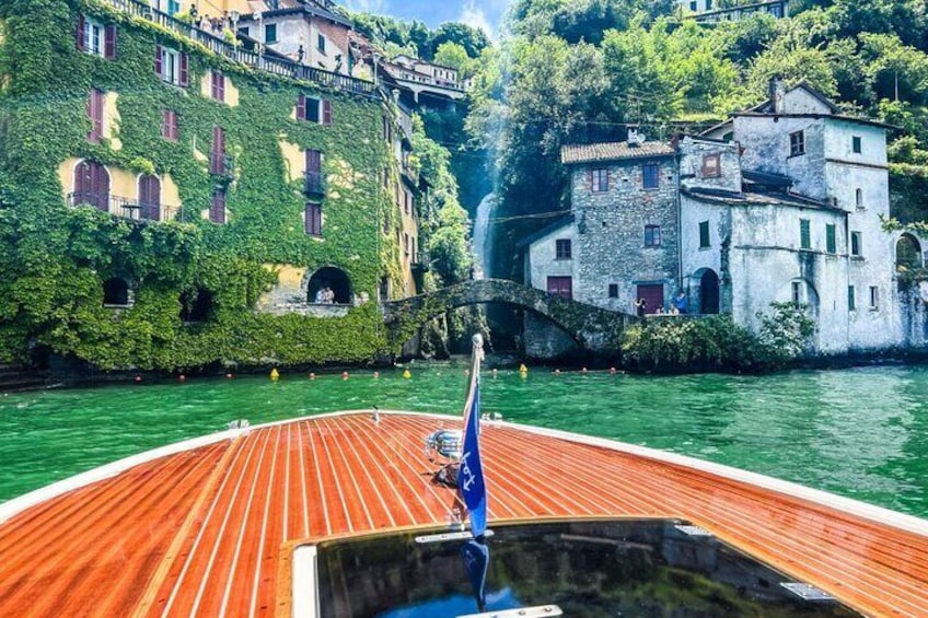 Un bote de madera en un río, con edificios cubiertos de vegetación en las orillas. 4
