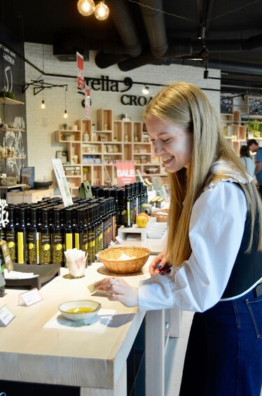 A person at a counter with a basket, a bowl, and bottles of olive oil. 5