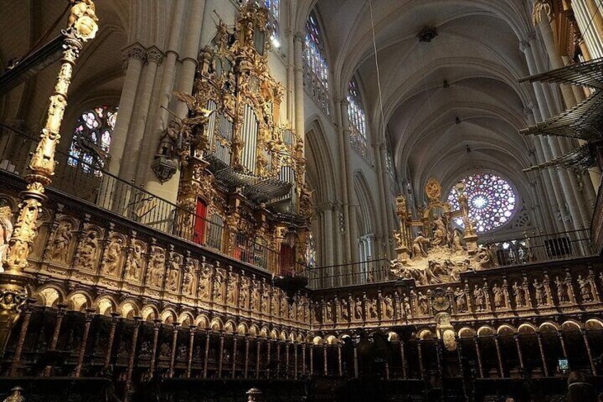 Een rijk versierd kathedraalinterieur met hoge gewelfde plafonds, ingewikkelde gouden beelden en een groot glas-in-loodraam. 1