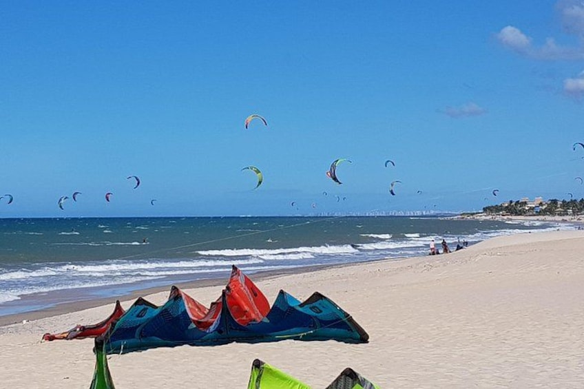 A beach with kites flying, a clear sky, and the ocean. 4