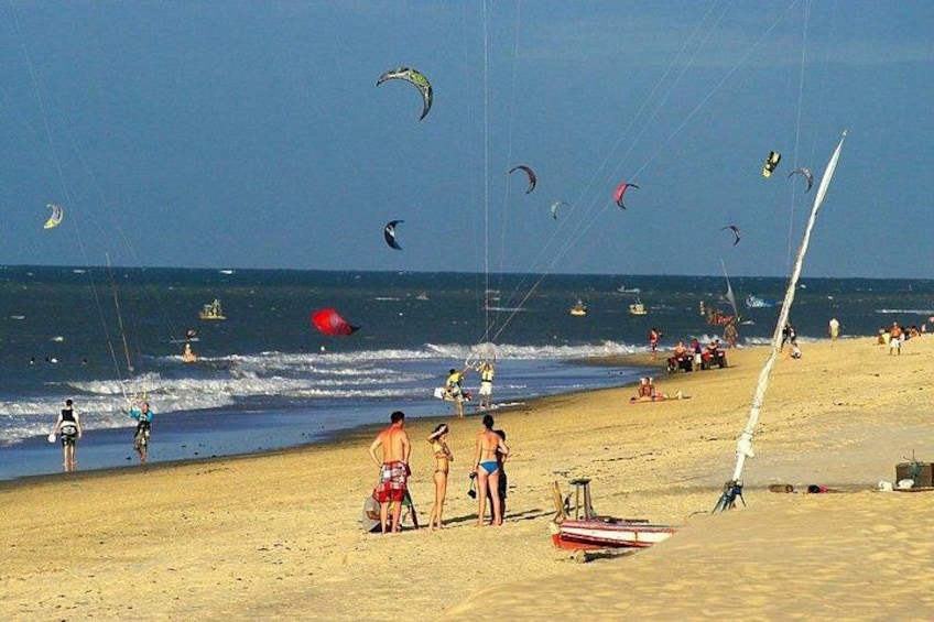 A beach with people, kites, and a sailboat. 5