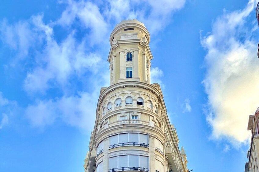 Ein hohes, verziertes Gebäude mit zahlreichen Balkonen und Fenstern vor blauem Himmel mit Wolken. 4