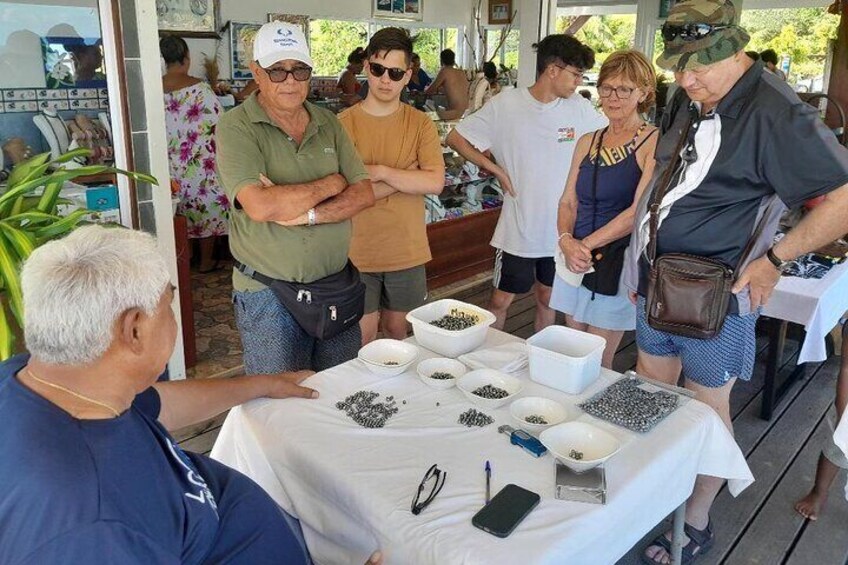 A group of people at an outdoor event with a table displaying various seeds. 4