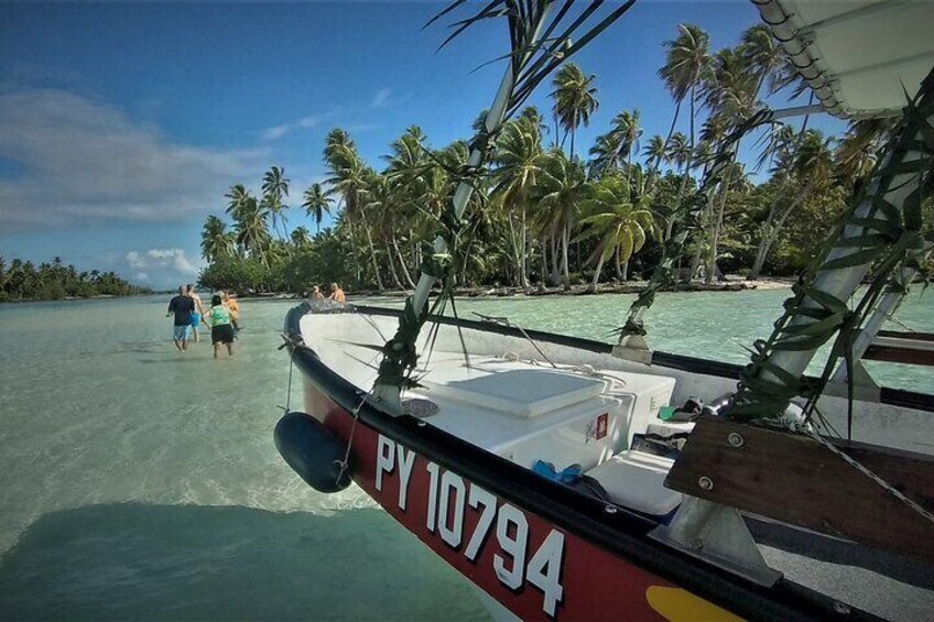 A boat with the registration PY 10794 on a clear day, surrounded by palm trees and calm turquoise waters. 1