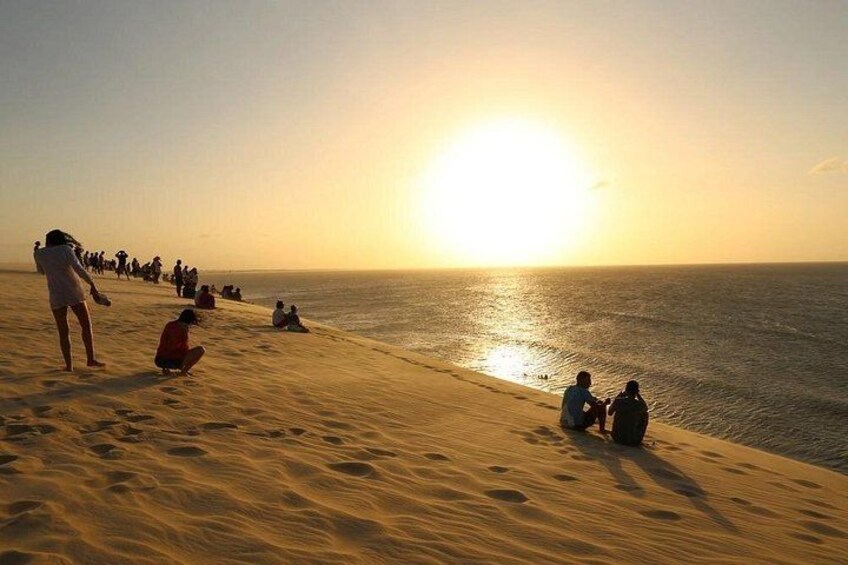 A beach at sunset with people sitting and walking along the shore. 3
