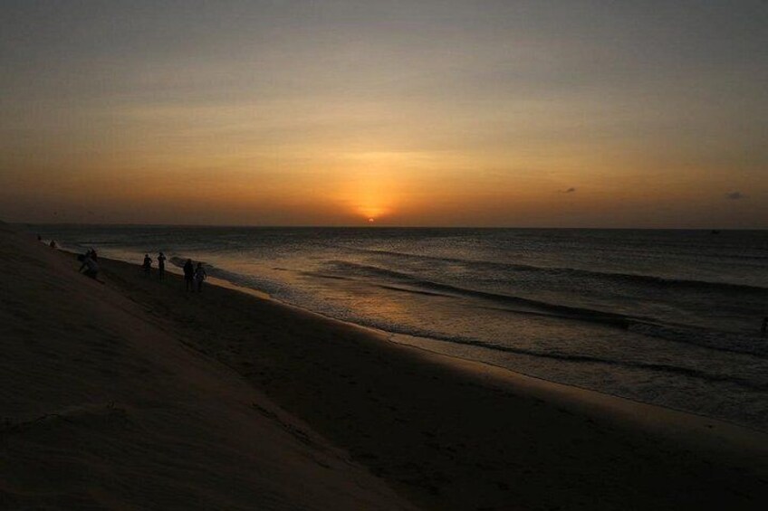 A beach at sunset with people walking along the shore. 2
