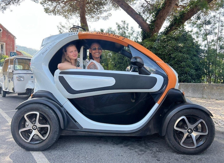 Un'auto piccola e moderna dal design originale, parcheggiata su una strada alberata con un edificio sullo sfondo. 5