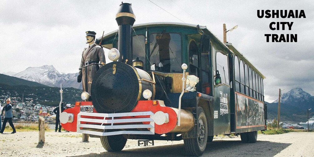 Un tren turístico antiguo en Ushuaia, con locomotora a vapor, pasajeros y un telón de fondo montañoso. 1