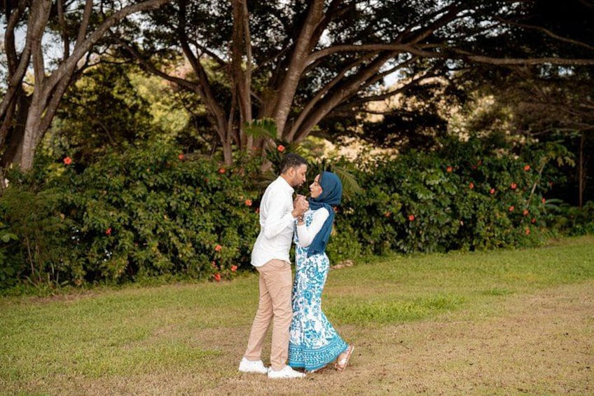 A couple embracing in a park with trees and bushes in the background. 3