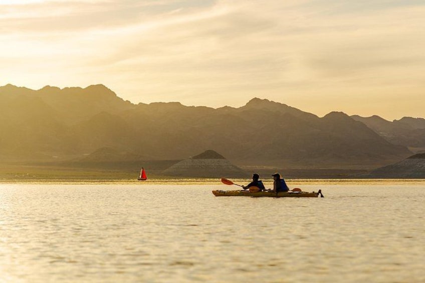 Two people kayaking on a calm lake with mountains in the background. 3